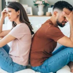 A couple sitting apart on the couch, showing emotional distance — representing how to break up with someone respectfully