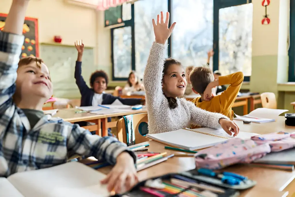 Smiling schoolgirl and classmates raising hands during a lesson — showing engagement during how many days in a school year students attend school
