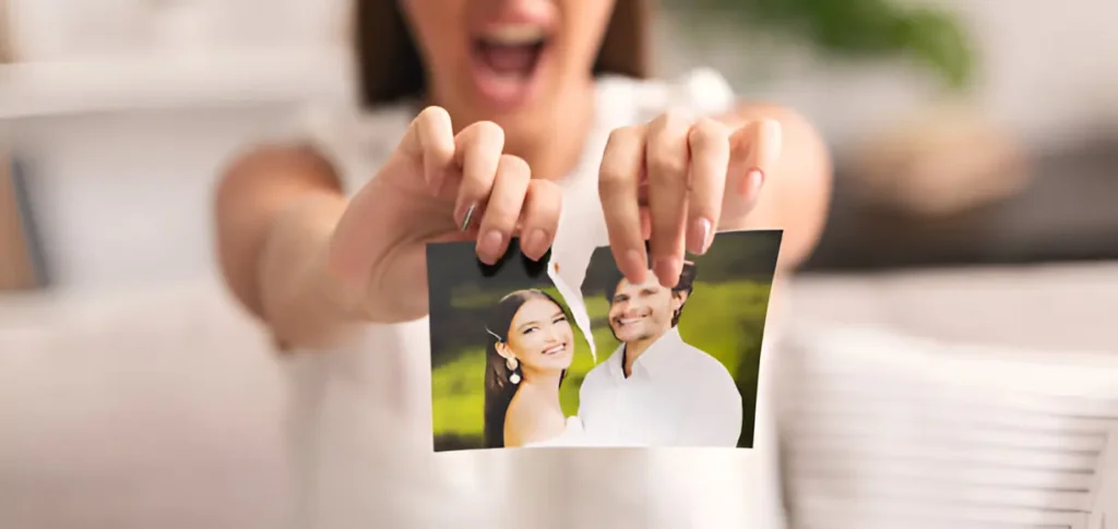 A woman tearing a photo of a happy couple, symbolizing how to break up with someone and move on
